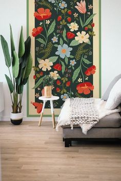 a living room with a couch, plant and wallpaper on the wall in front of it