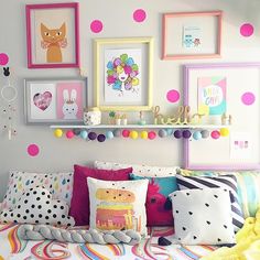 a bed topped with lots of pillows and pictures on the wall above it's headboard