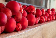 red ornaments are lined up on a shelf