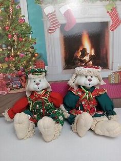 two stuffed animals sitting next to each other in front of a christmas tree and fireplace