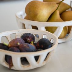 two white bowls filled with fruit sitting on top of a counter next to each other