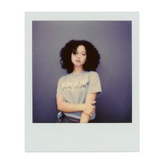 an old photo of a woman with her arms crossed in front of the camera, against a blue wall