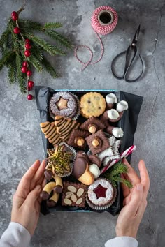 someone is holding their hands over a tray of cookies and pastries on a table