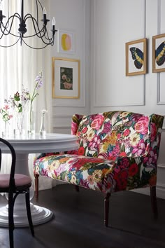 a colorful floral chair sits in front of a white table with flowers and butterflies on it