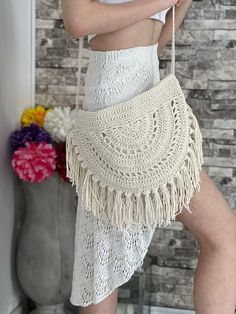 a woman is wearing a white crochet bag