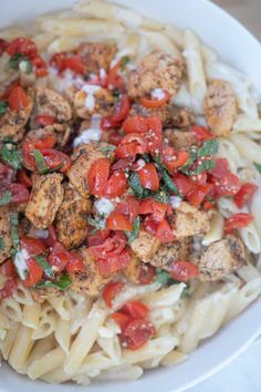 pasta with chicken, tomatoes and spinach in a white bowl