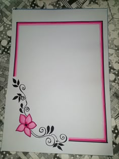 a white and pink frame with flowers on the edge is sitting on a quilted surface