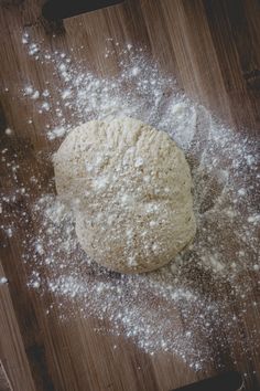 a wooden table topped with lots of white powder next to a knife and bowl filled with flour