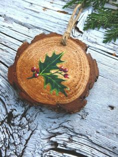 a wooden ornament with holly leaves and berries on it hanging from a rope