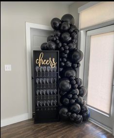 black balloons and champagne glasses in front of a sign that says cheers on the wall