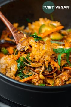 a close up of food in a pan with a wooden spoon