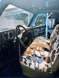 the interior of an old truck with cow print upholstered seats and steering wheel