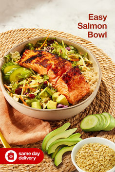 a bowl filled with salmon and vegetables next to sliced cucumbers