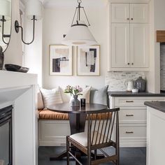 a kitchen with a table and chairs in front of a white cupboards filled with cabinets