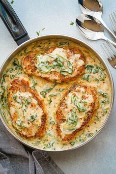 a pan filled with chicken patties covered in cheese and sauce next to silverware