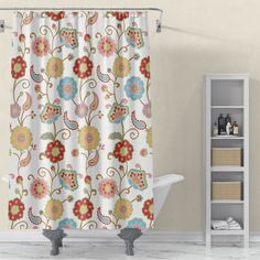 a shower curtain with colorful flowers on it in a white bathroom next to a bathtub