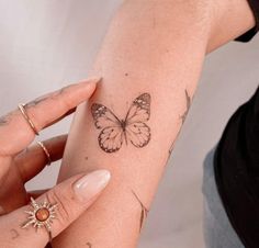 a woman's arm with a small butterfly tattoo on the left side of her arm