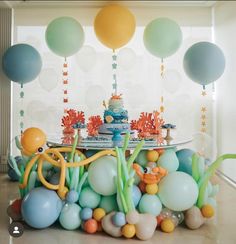 an under the sea themed birthday party with balloons, cake and decorations on a table