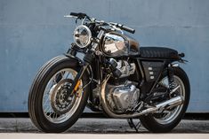 a black motorcycle parked next to a blue wall