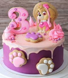 a birthday cake decorated with pink and purple icing, paw prints and dog's name