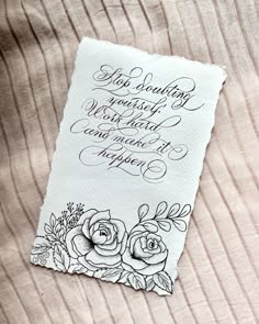 a piece of paper with writing on it and some flowers in the corner next to it