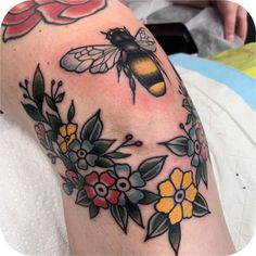 a woman's arm with flowers and a bee on it