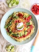 a bowl filled with pasta, tomatoes and lettuce on top of a table