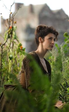 a woman standing in the middle of some plants