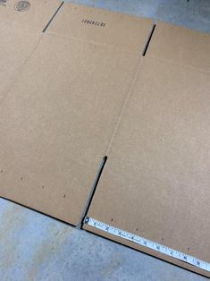 two cardboard boxes are laying on the floor with a ruler in front of them,