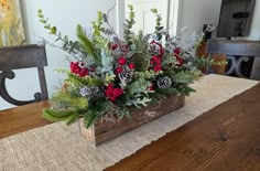 a wooden box filled with red berries and greenery sitting on top of a table