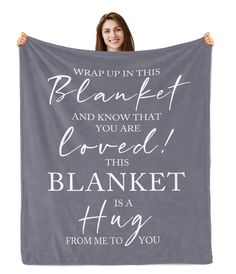 a woman holding up a blanket that says, wrap up in this blanket and know that loved