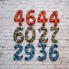 the letters and numbers are made out of mosaic tiles on a white brick wall,