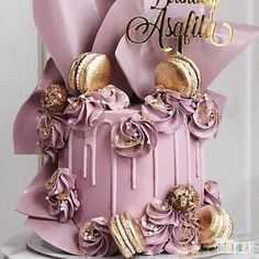 a pink cake with gold decorations on top and a happy birthday card in the background