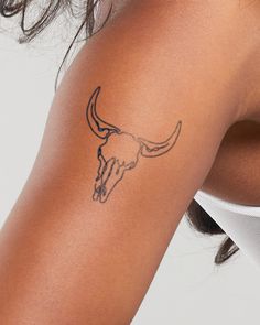 a woman's arm with a tattoo of a bull skull on the left side