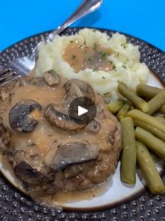 a plate with mashed potatoes, green beans and mushrooms on it next to gravy