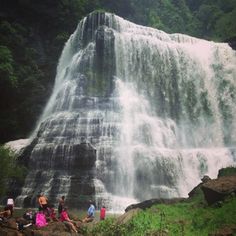 people are sitting at the base of a waterfall