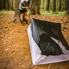 the man is setting up his tent in the woods