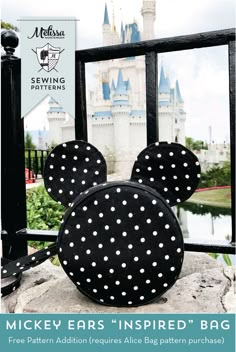 the mickey ears inspired bag is on display in front of a castle with its reflection