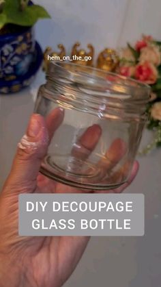 a hand holding a glass bottle with the text diy decoupage glass bottle