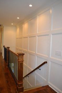 an empty room with wood floors and white walls, along with a staircase leading up to the second floor