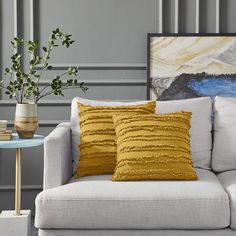 a couch with two pillows on top of it next to a table and potted plant