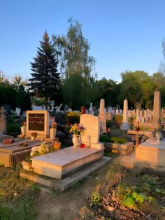 an old cemetery with headstones and flowers in the foreground, at sunset or dawn