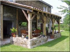 an outdoor covered patio area with chairs and potted plants on the grass next to it