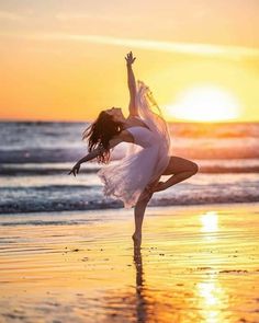 a woman is dancing on the beach at sunset