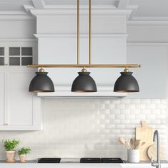 a kitchen with three lights hanging over the stove and counter top, next to a potted plant