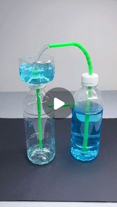 two water bottles with drinking straws attached to the top one is filled with blue liquid