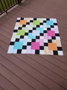 a multicolored patchwork quilt on a deck