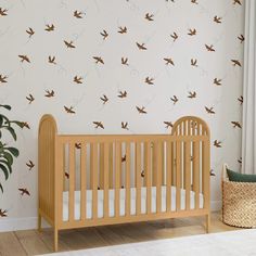 a baby crib in front of a wall with birds on it