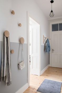 an entryway with coat hooks and rugs on the wooden floor next to it