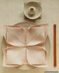 an arrangement of plates, utensils and chopsticks sits on a table